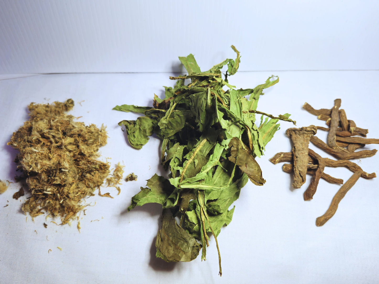 A picture showing the component parts of the dandelion forage. A small pile of dandelion flowers, dandelion leaves and dandelion roots.