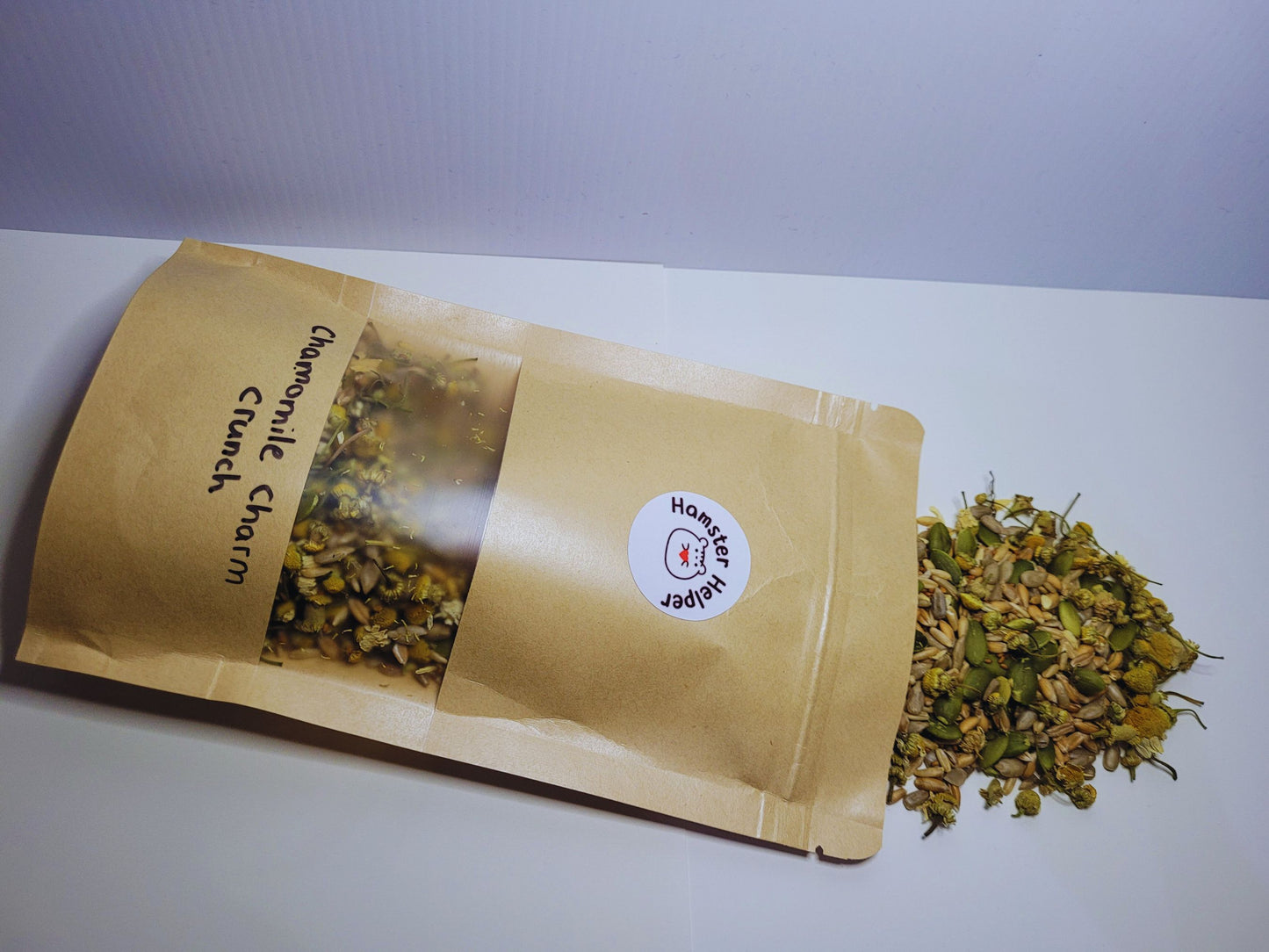 A picture of the chamomile charm crunch hamster treat mix pouch on its side with the treat mix spilling out