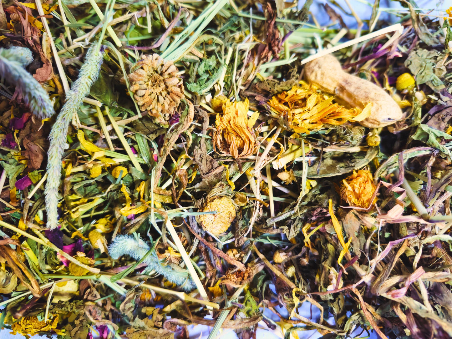 A close up of the hamster safe forest forage containing hay, leaves, dried flowers and snacks.