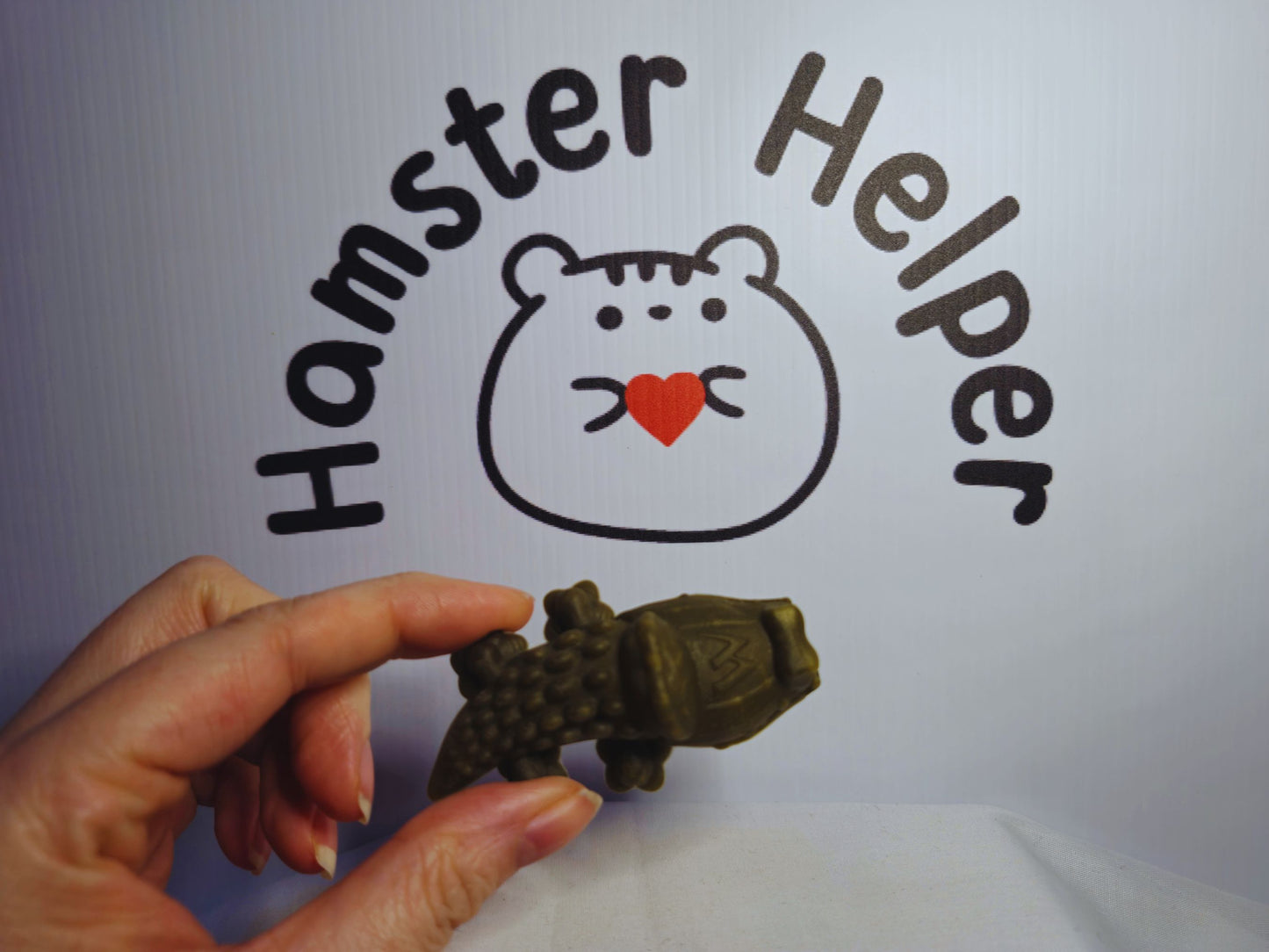 A hand holding the hamster safe alligator whimzee to demonstrate the size of the whimzee.