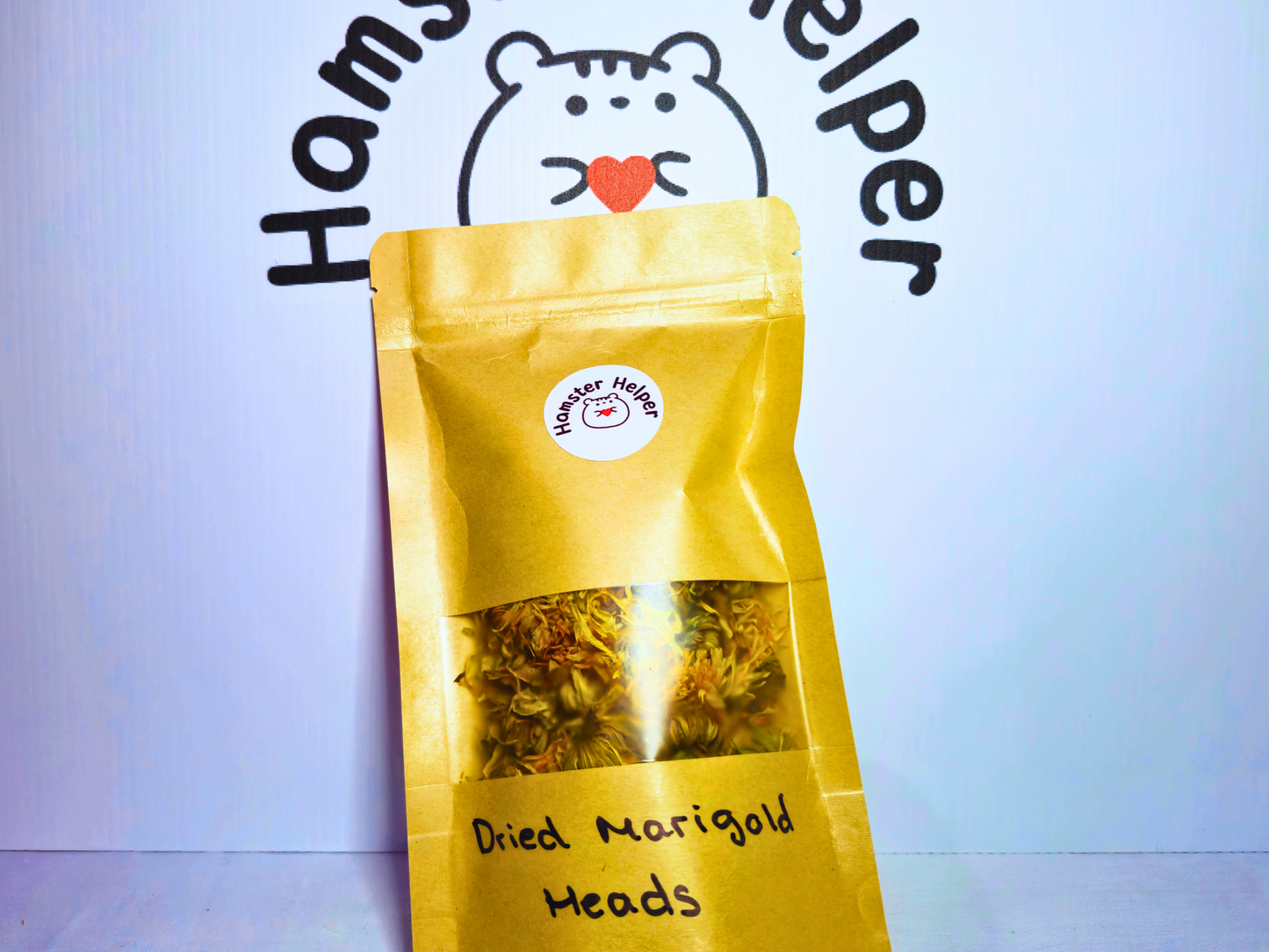 Dried marigold heads for hamsters in a pouch with the Hamster Helper logo on it in front of a Hamster Helper sign.