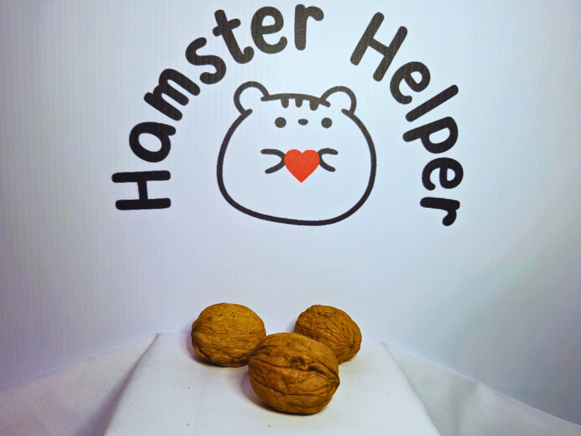 Three walnuts in shells used as hamster chews in front of the Hamster Helper logo.