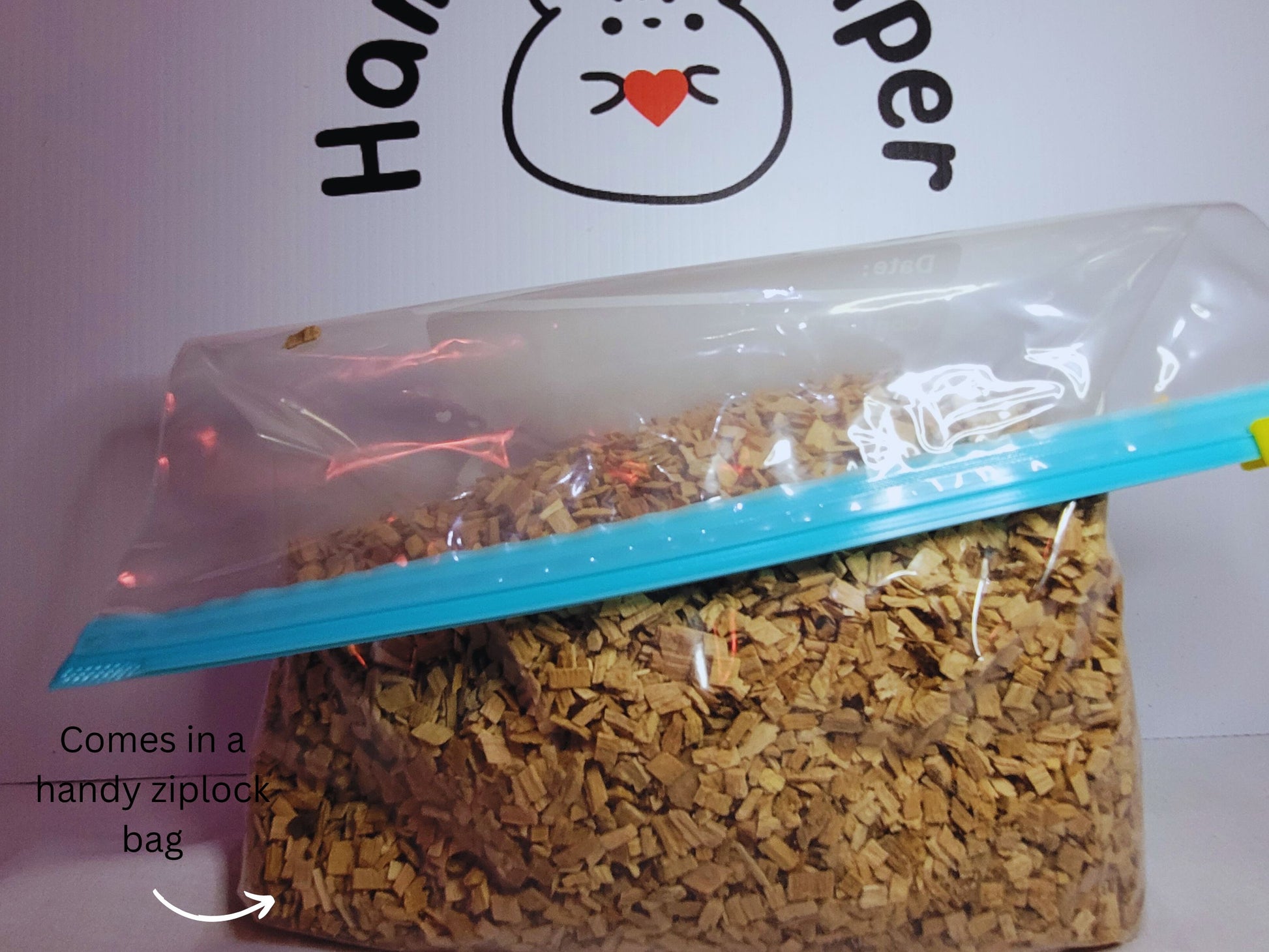 A ziplock bag containing hamster safe beech chips in front of the Hamster Helper logo