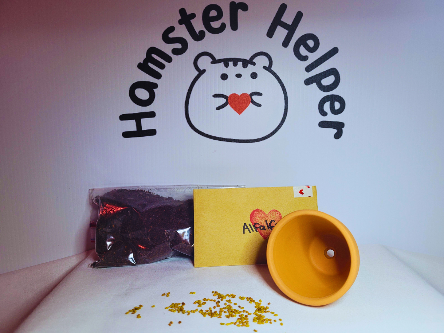 A hamster safe alfalfa microgreen kit containing soil, seeds and a terracotta pot in front of the Hamster Helper logo