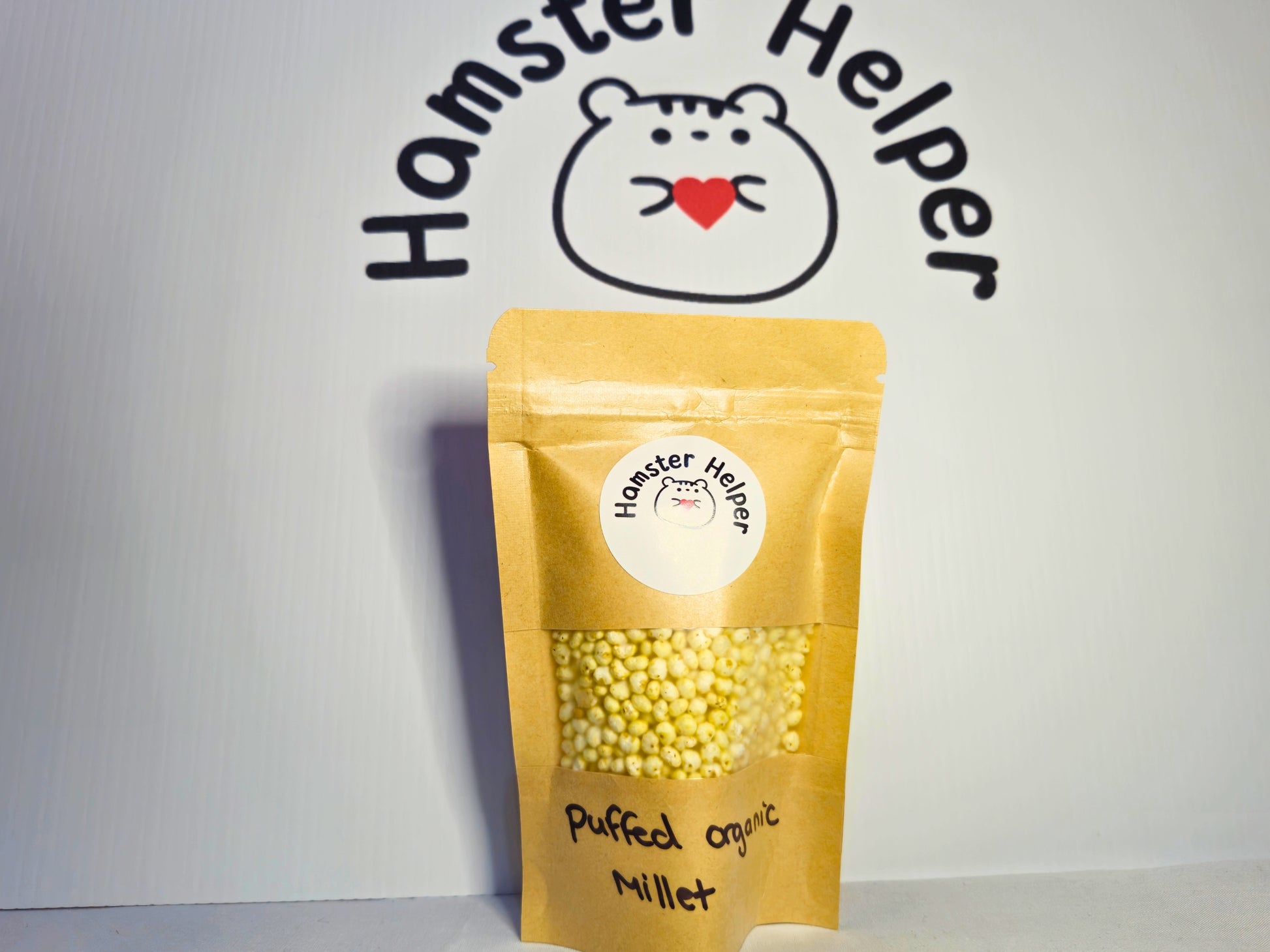 A small pouch of hamster safe puffed organic millet in front of the Hamster Helper logo.