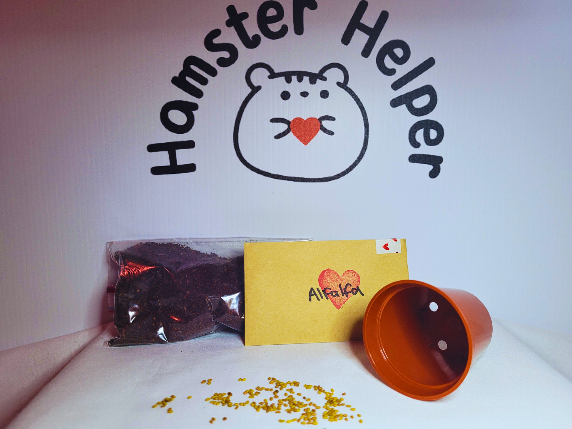 A hamster safe alfalfa microgreen kit for hamsters with a plastic plant pot in front of the Hamster Helper logo