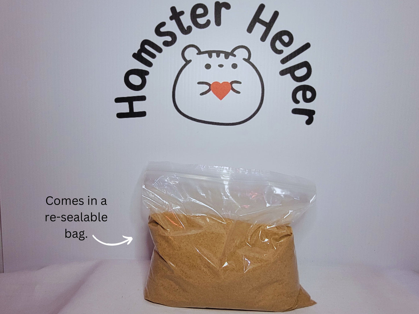 A re-sealable bag containing hamster safe sand displayed in front of the Hamster Helper logo