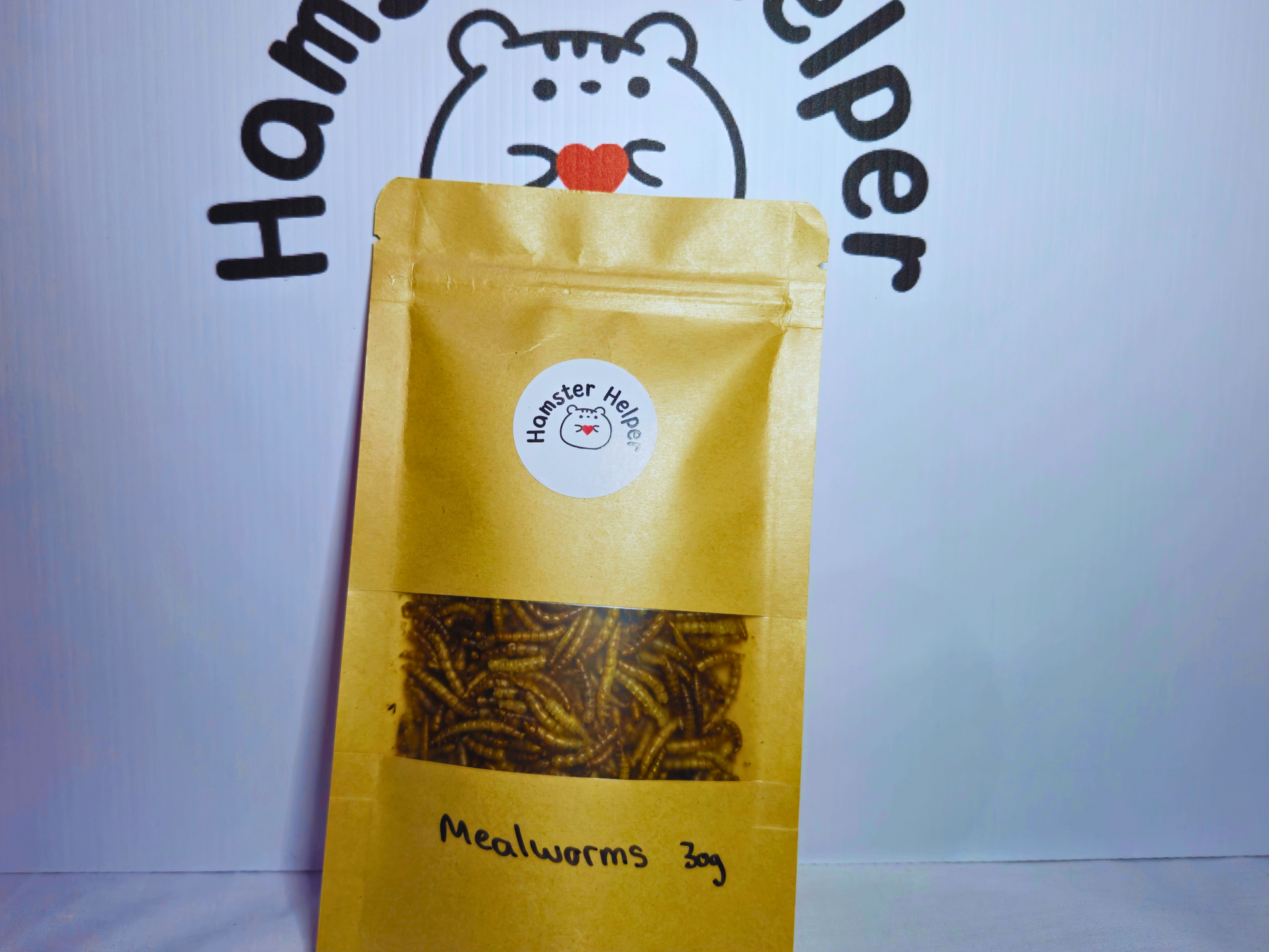 A re-sealable bag containing hamster safe meal worms in front of the hamster helper logo